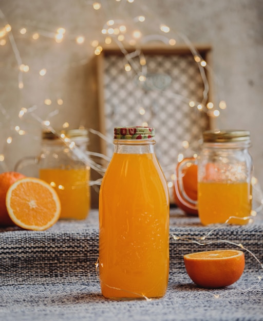 Vista laterale di succo d'arancia in una bottiglia di vetro sul tavolo