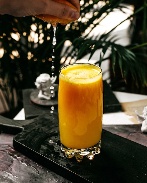 Side view of orange juice on a wooden cutting board