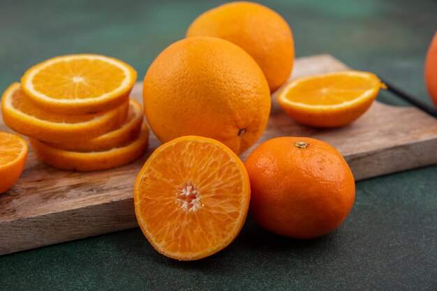 Side view orange slices on a cutting board on a green background