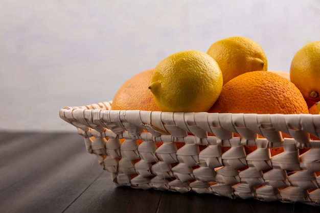 Апельсины в корзине с лимонами и грейпфрутами, вид сбоку