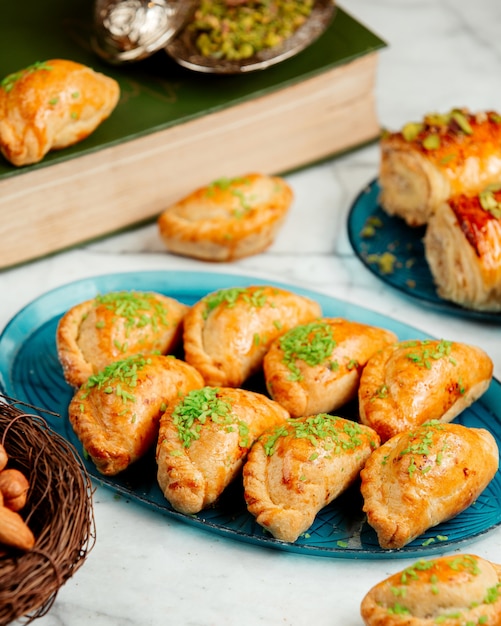 Side view of oriental pastry with nuts and pistachio on platter