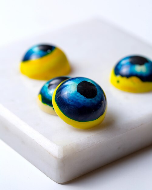 Side view painted blue eyes in the form chocolate sweets on white stand