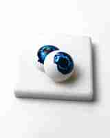 Free photo side view painted blue eyes in the form chocolate sweets on white stand