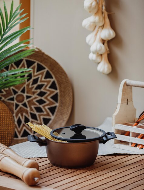 Side view of a pan with raw spaghetti on a wooden table