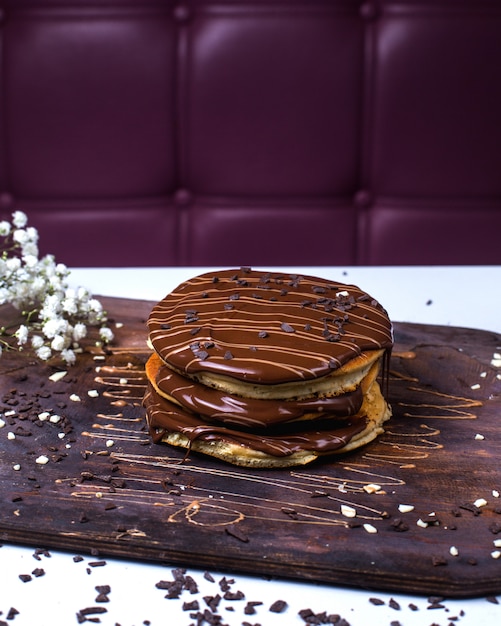 Side view of pancake with chocolate on a wooden board