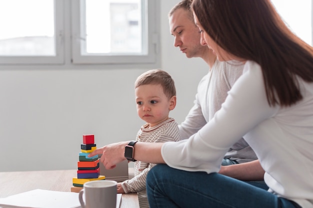 Вид сбоку родителей с ребенком, играющим дома