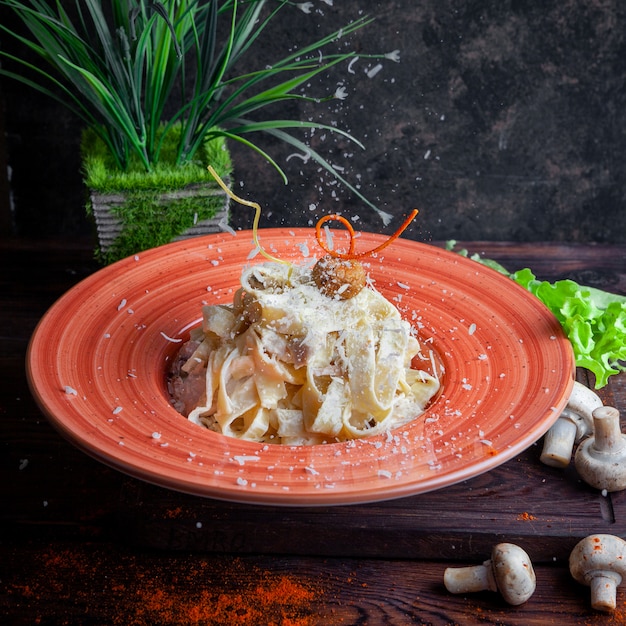 Vista laterale pasta con salsa, parmigiano, funghi, lattuga