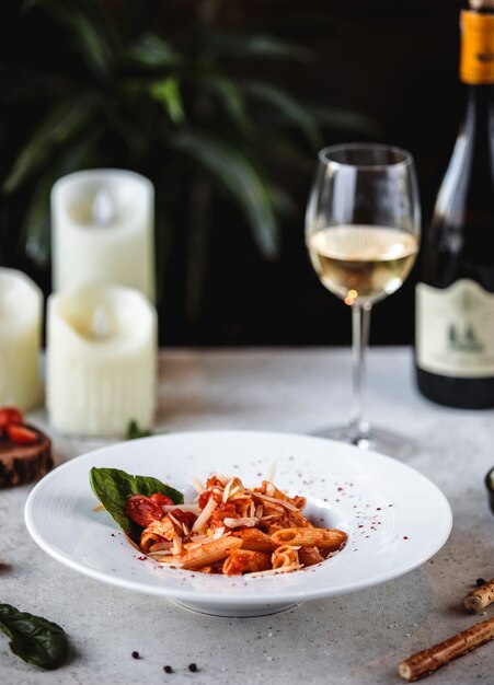 Side view of pasta with tomato sauce and parmesan cheese in white bowl