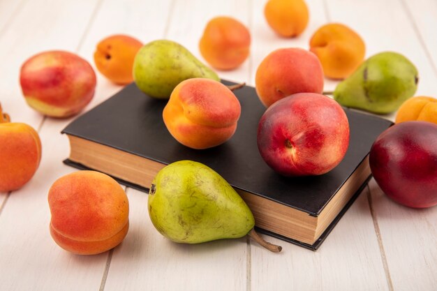 Side view of pattern of fruits as peach and pear on closed book and on wooden background