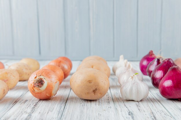 Side view of pattern of vegetables as onion potato garlic on wooden surface and background with copy space