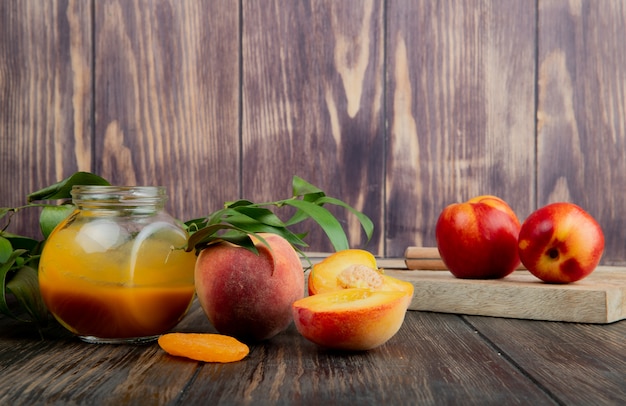 Вид сбоку персикового джема в стеклянной банке и свежих спелых персиков на деревянном фоне