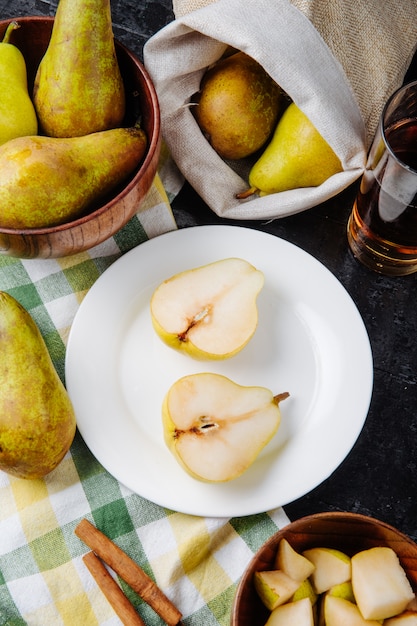 Side view of pear halves on a white plate and a glass of lemonade on a plaid tablecloth