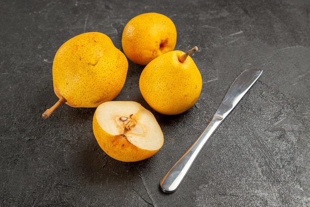 Free photo side view pears and knife knife three yellow pears and half a pear on the dark surface