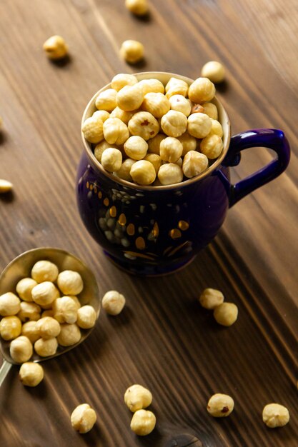 Side view peeled hazelnuts in a jug with a spoon on the table