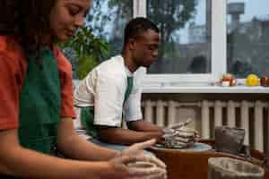 Free photo side view people doing pottery