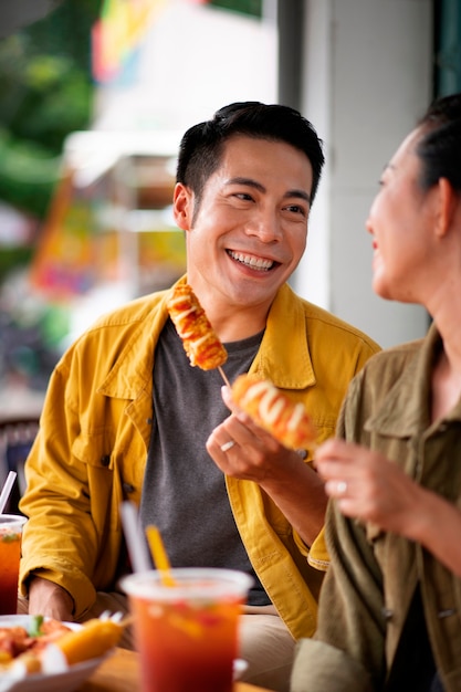 Free photo side view people eating corn dogs