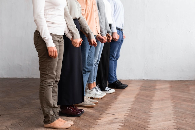 Vista laterale di persone che si tengono per mano in una sessione di terapia di gruppo