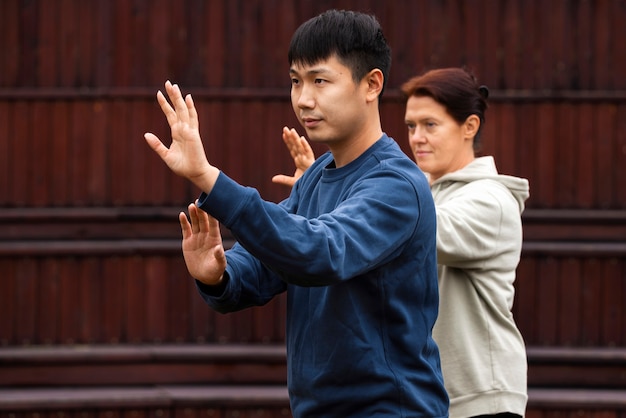 Foto gratuita persone di vista laterale che praticano il tai chi