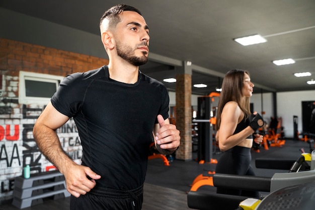 Free photo side view people running on treadmill at gym