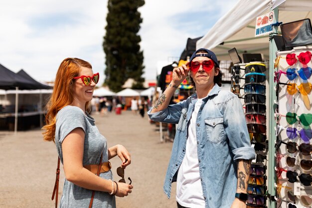 Side view people trying on sunglasses