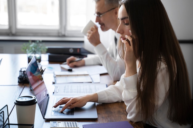 Foto gratuita persone di vista laterale che lavorano alla scrivania