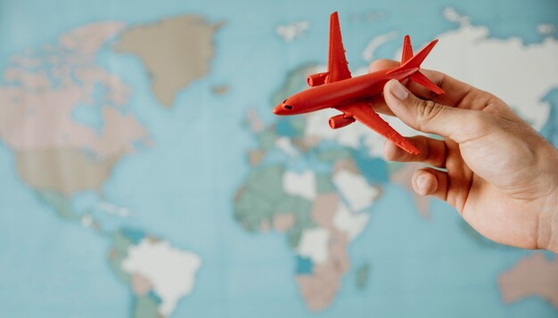 Free photo side view of person holding airplane figurine over map