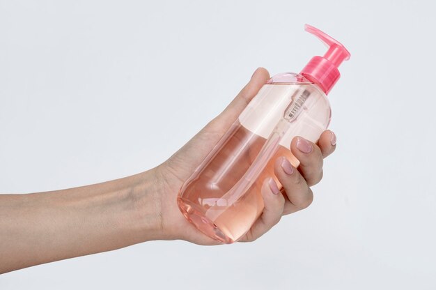 side view person holding a bottle of liquid soap