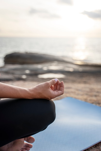 Side view person meditating on beach