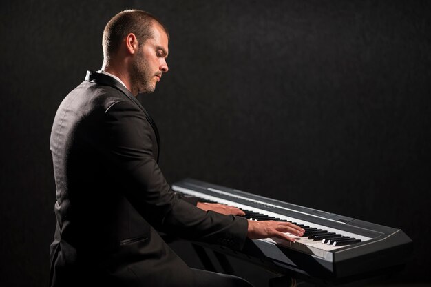 Вид сбоку человека, играющего на цифровом миди-пианино