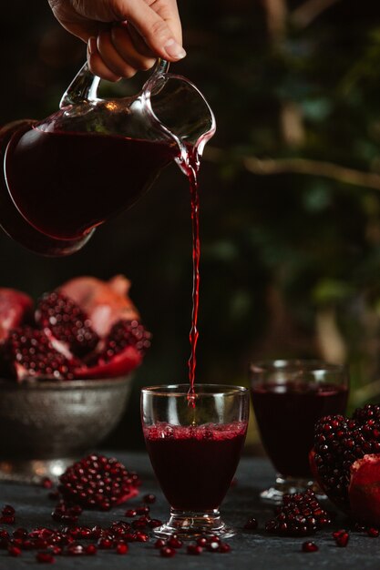 Side view of a person pouring fresh pomegranate juice into a glass jpg