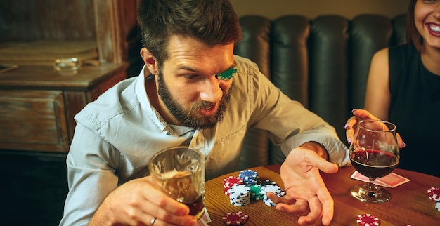 Side view photo of friends sitting at wooden table. Friends having fun while playing board game.