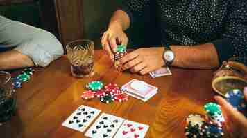 Free photo side view photo of friends sitting at wooden table. friends having fun while playing board game.