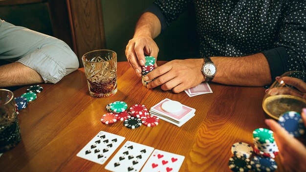 Side view photo of friends sitting at wooden table. Friends having fun while playing board game.