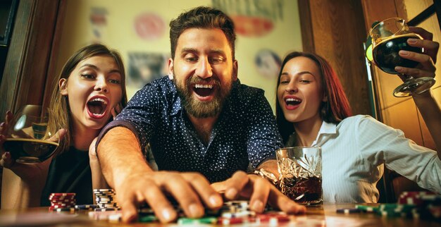 Фото взгляда со стороны друзей сидя на деревянном столе. Друзья веселятся во время игры в настольную игру.