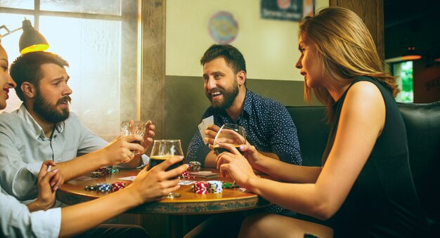 Side view photo of male and female friends sitting at wooden table.