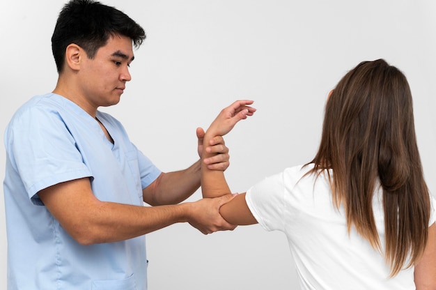 Free photo side view of physiotherapist doing elbow exercises with woman