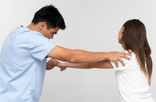 Free photo side view of physiotherapist doing shoulder exercises with woman