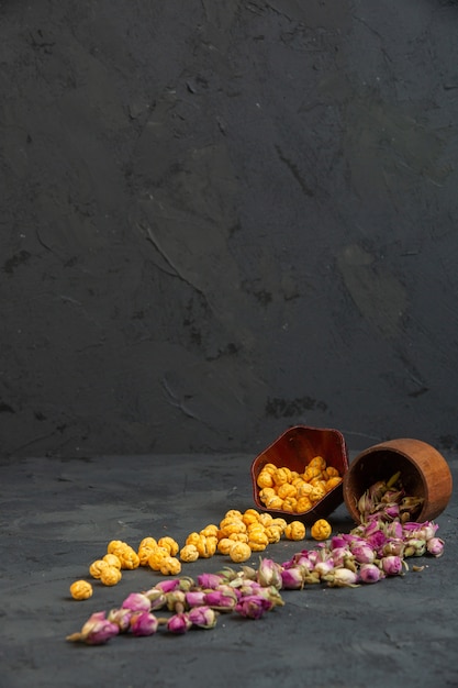 Бесплатное фото Вид сбоку розовые сухие розы, разбросанные по корзине с посыпанной сладким попкорном