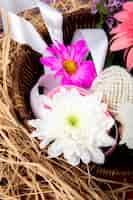 Free photo side view of pink and white color chrysanthemum flowers with gerbera and lilac flower in a wicker basket with straw on purple background