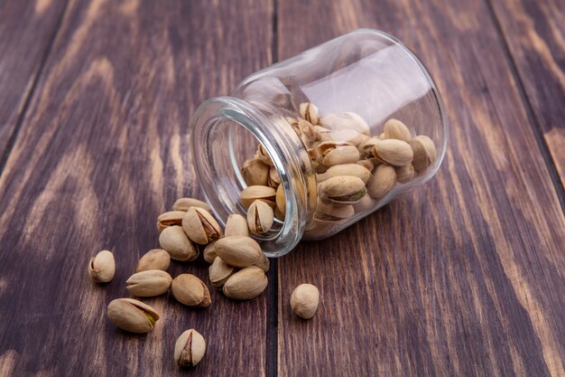 Side view of pistachios in a jar on a wooden surface