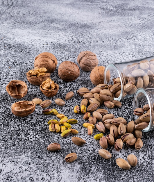 Free photo side view pistachios and walnut in glass