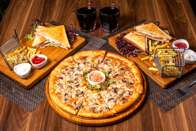 Вид сбоку пиццы с курицей и грибами, подается с салатом из соуса и овощей на деревянной тарелке