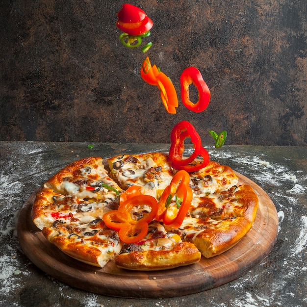 Side view pizza with slices of bell pepper and pizza slices and flour in board cookware