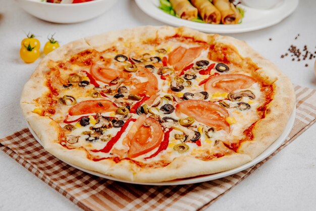 Side view of pizza with tomatoes mushrooms and olives