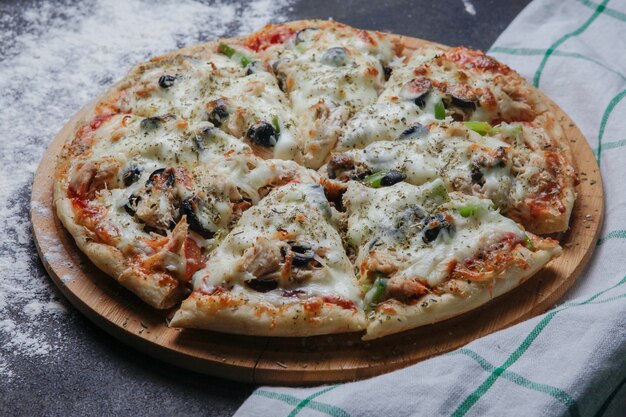 Side view pizza on a wooden stand with a tablecloth horizontal