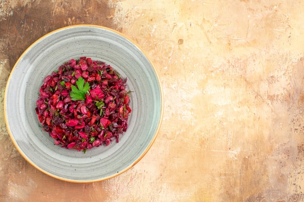 Side view of plate of a red salad with greens on it on a wooden backgorund