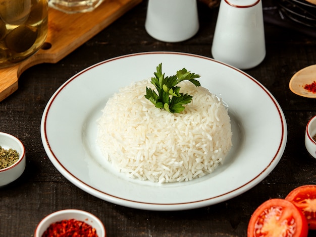 Side view of a plate with cooked rice with parsley on the table