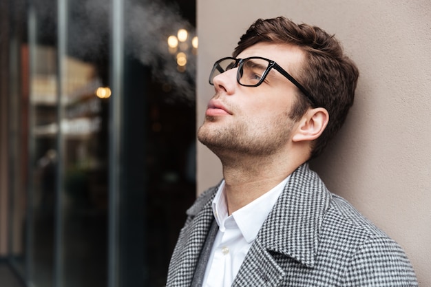 Side view of pleased businessman in eyeglasses and coat