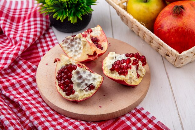 Side view of pomegranate slices on a stand with a red checkered towel on a white surface