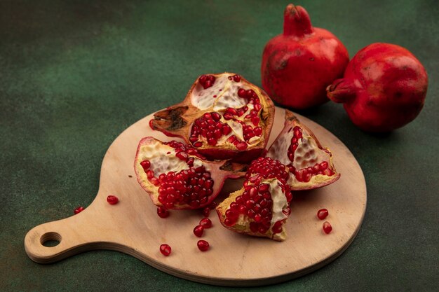 Side view pomegranate wedges on a cutting board on a green wall